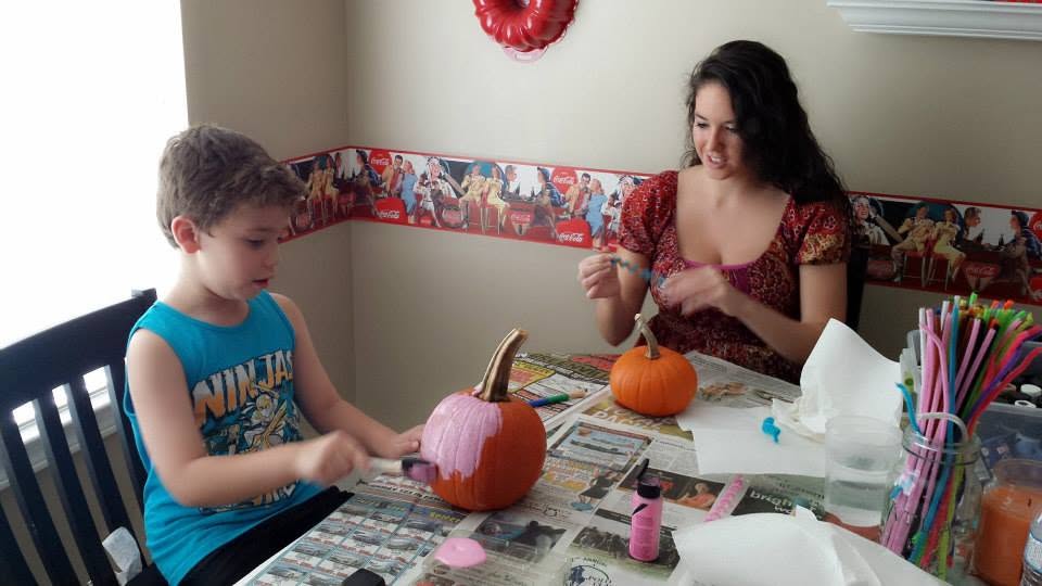 Nanny and child painting pumpkins
